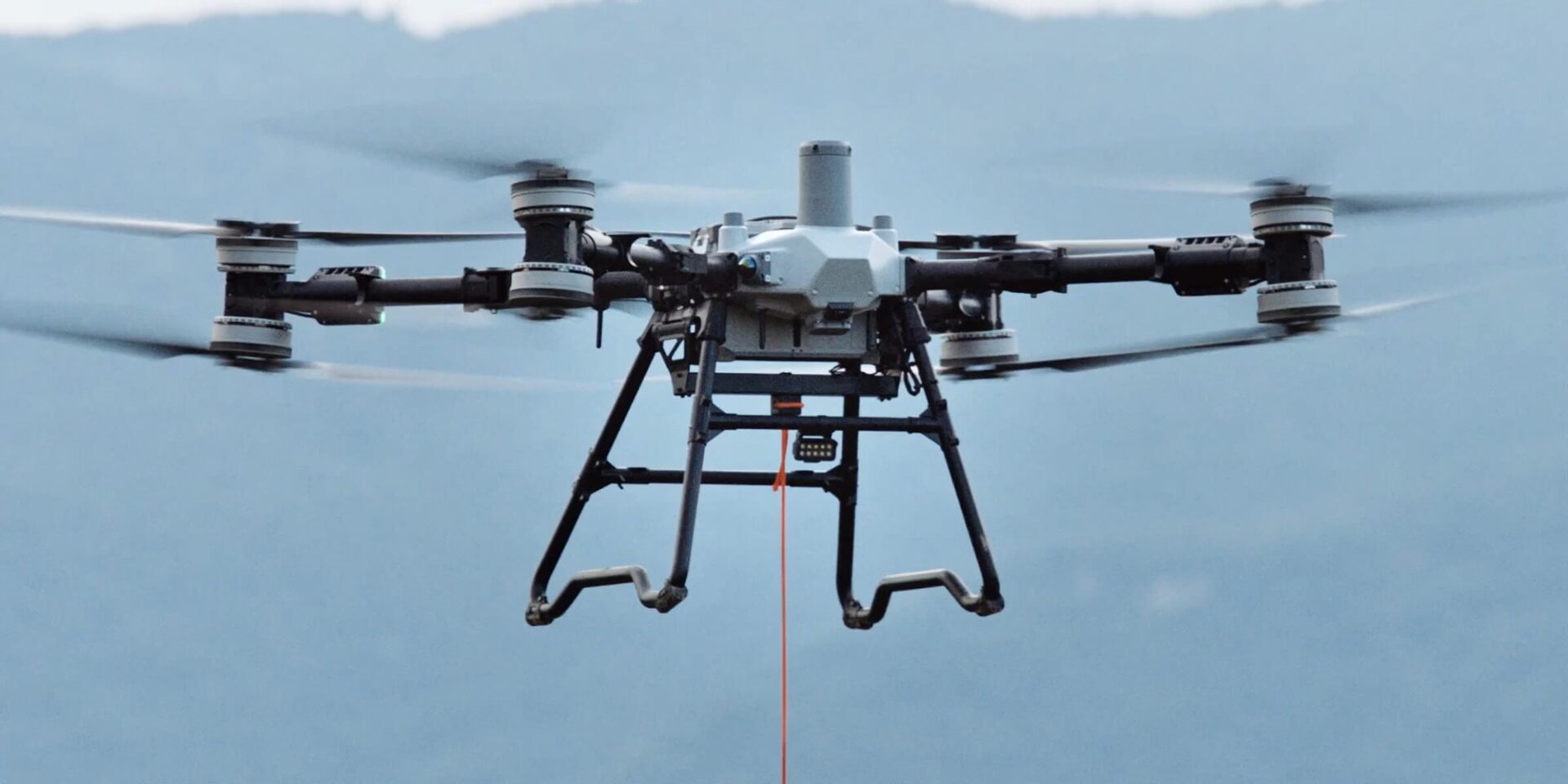 Transport ładunku DJI Agras T100 z systemem podnoszenia i ładunkiem na linie
