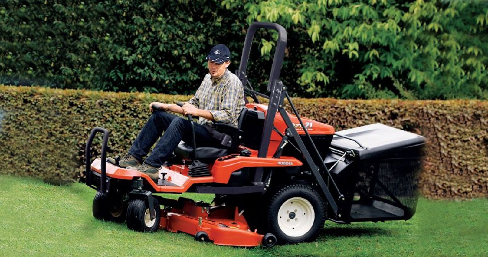 Kubota GZD15 – kosiarka zero-turn z koszem podczas koszenia trawnika przy żywopłocie