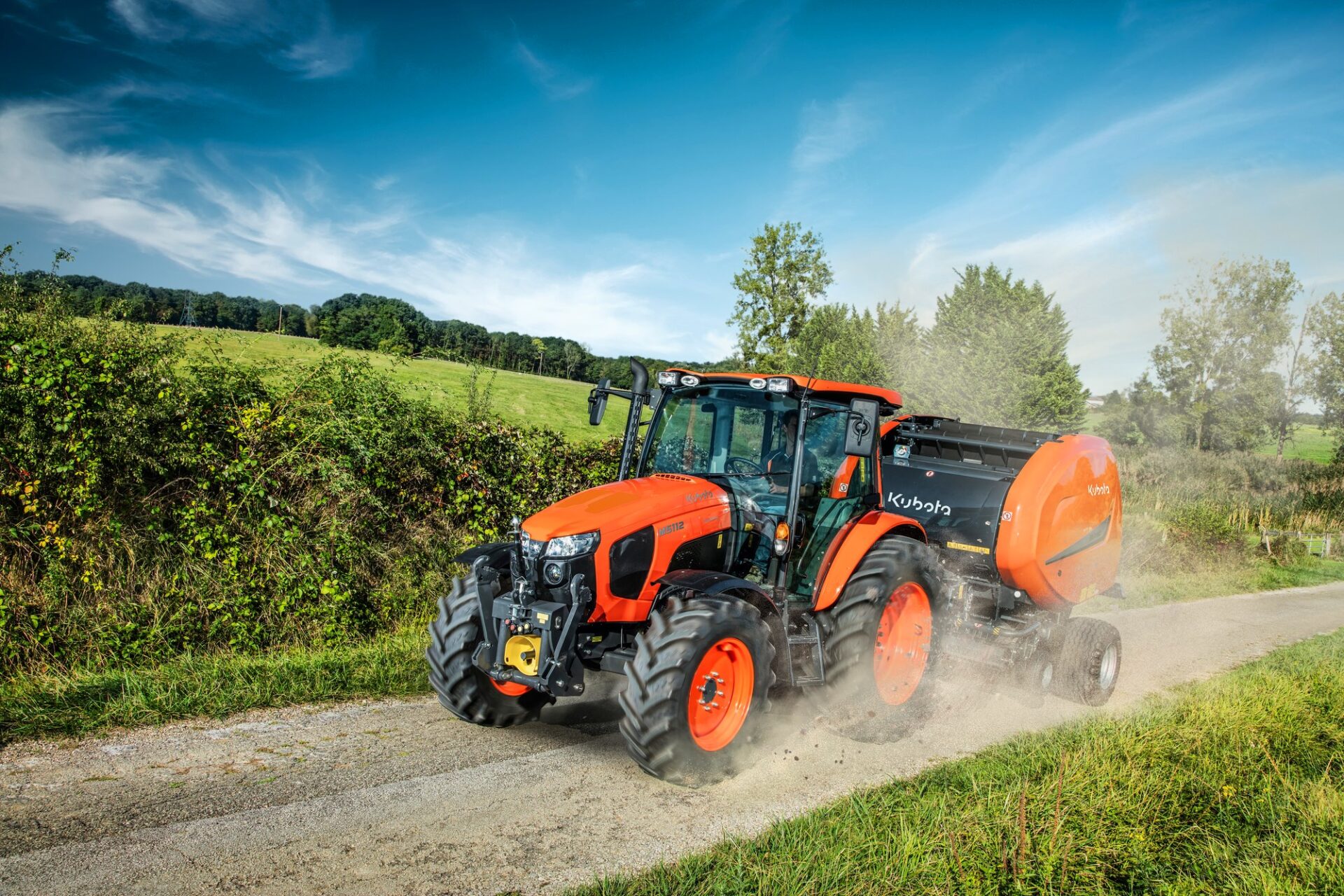 Ciągnik Kubota M5002 z prasą na polnej drodze