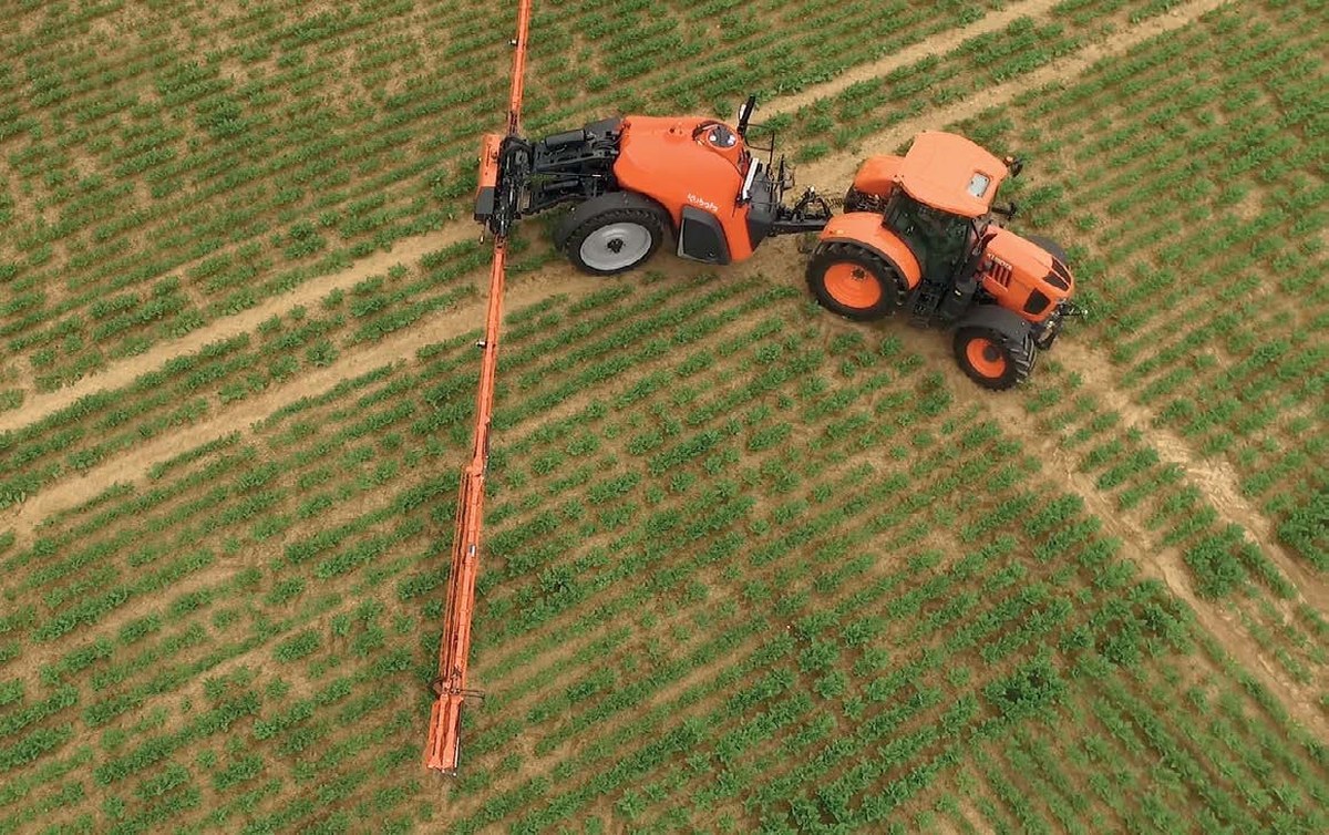 Ciągnik Kubota z opryskiwaczem ciąganym Kubota XTS i rozłożoną belką podczas zabiegu, widok z góry
