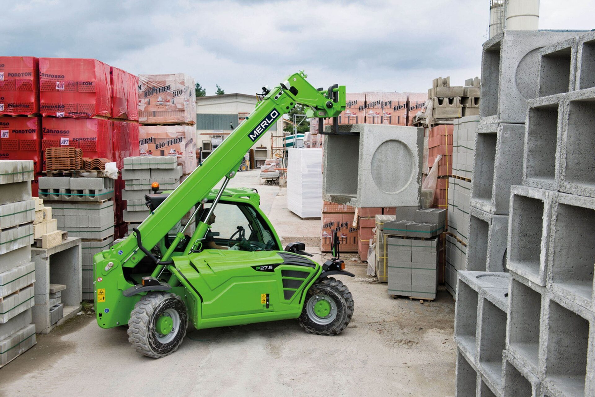 Merlo Panoramic P27.6 na składowisku Merlo Panoramic P27.6 z podniesionym wysięgnikiem na składowisku materiałów budowlanych