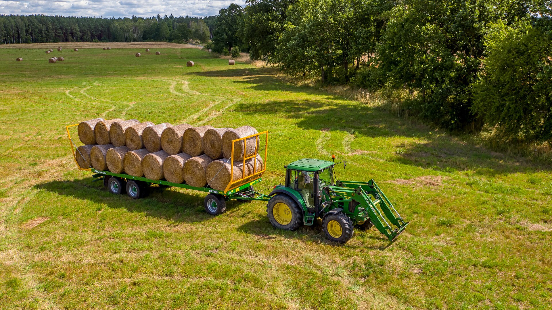 Transport bel Przyczepa do bel METALTECH PB z ciągnikiem na łące