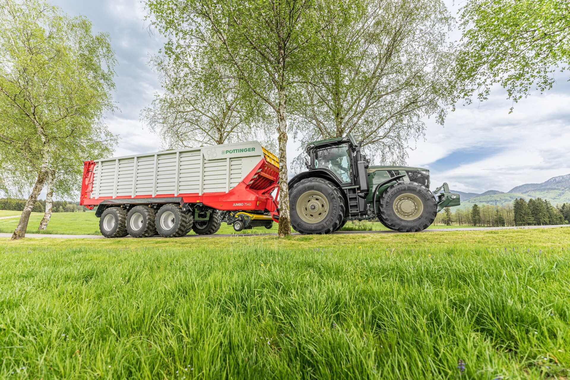 Przyczepa samozbierająca Pöttinger JUMBO 7540 z podwoziem tridem i ciągnikiem, widok z boku