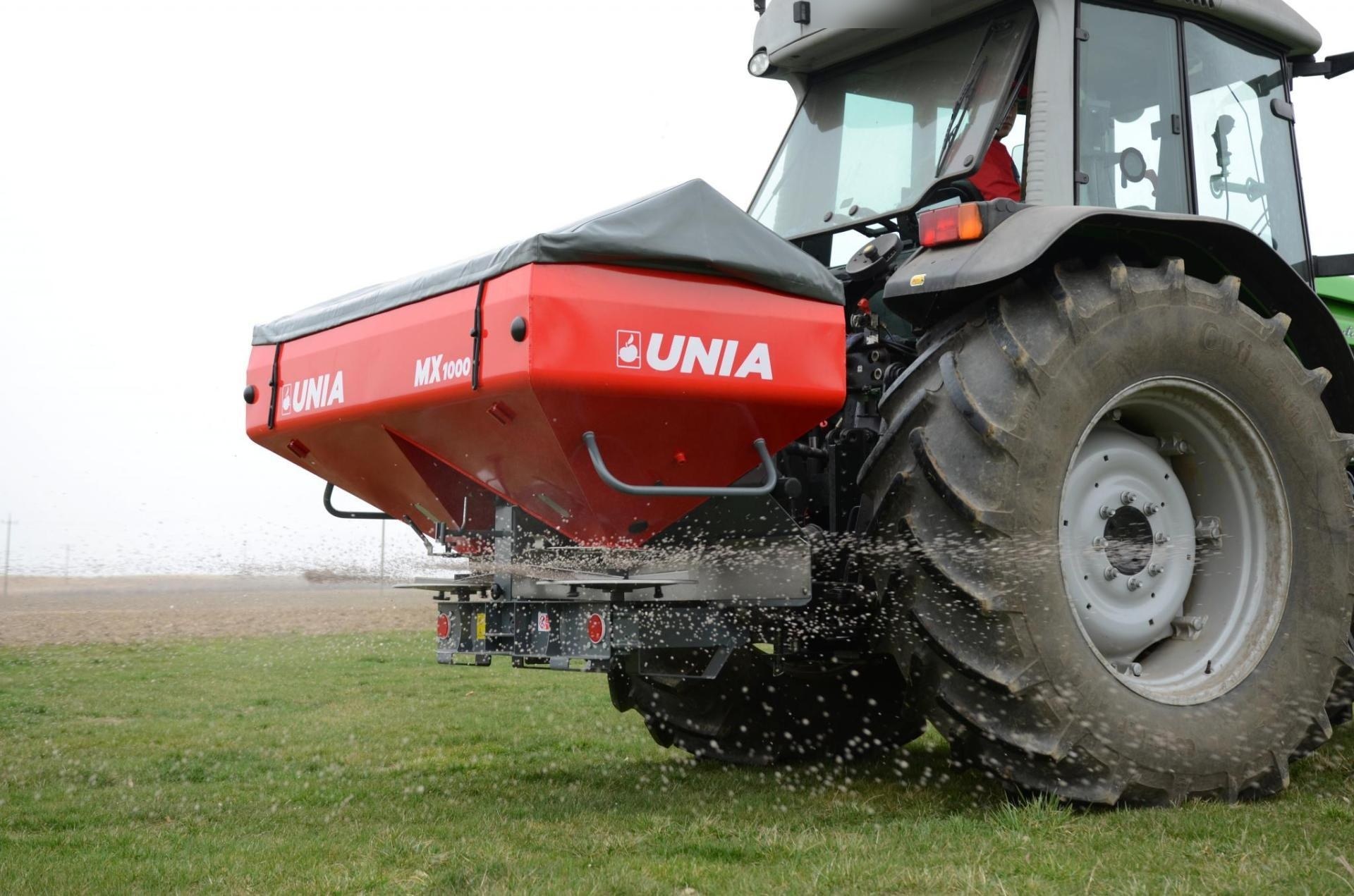 Rozsiewacz nawozów UNIA MX 1000 zawieszony na ciągniku podczas wysiewu nawozu